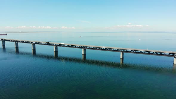 Drone spinning left, view over Øresundsbron, cargo ship crossing