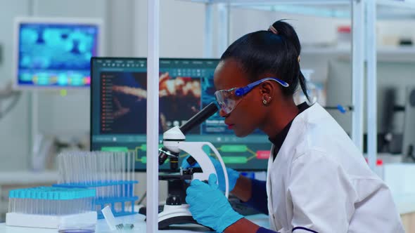 African Woman Biochemist Using Microscope in Laboratory