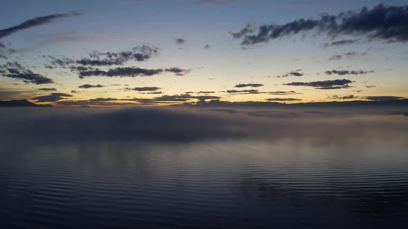 Flying low over Lake Léman with patches of fog reflecting in the water at sunsetVaud - Switzerland