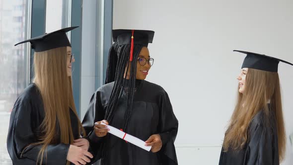 Three Female Students of Different Races with a Diploma in Their Hands
