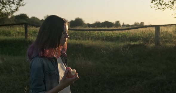 Young Happy Girl Walking and Eating Red Apple