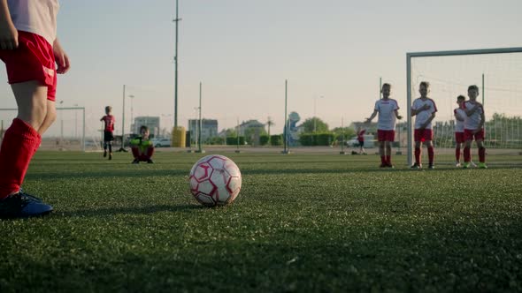 çSchoolboy Junior League Player Kicks Ball Low Angle Shot