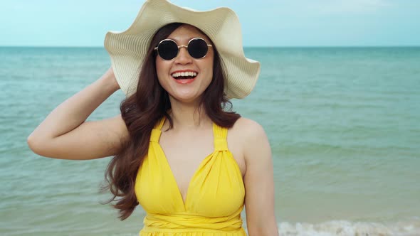 cheerful woman in yellow dress enjoying on the sea beach