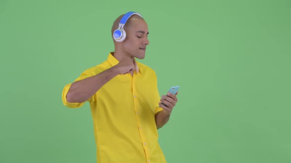 Happy Handsome Bald Businessman Using Phone and Listening To Music