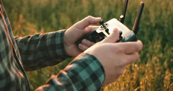 Close up shot of male person flying drone with controller pushing joystick during sunset in nature