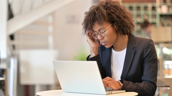 Stressed African Businesswoman with Laptop Having Headache at Cafe 