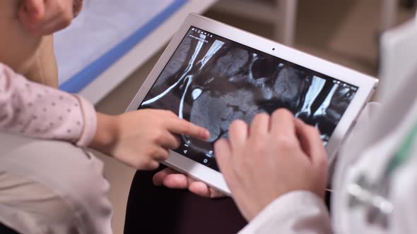 Doctor Holding Tablet with Brain Scans on Screen