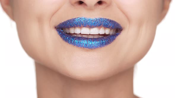 Extreme Close Up Portrait of Happy Female Lips Covered with Blue Shining Glitter Giving Air Kiss