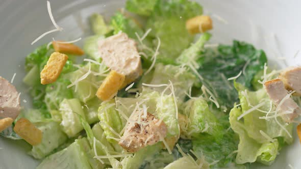 Camera follows putting caesar salad in a plate. Slow Motion.