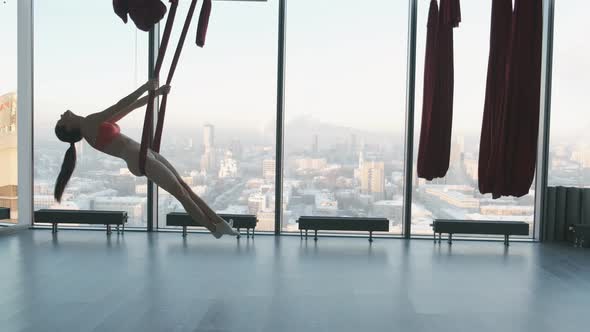 Woman Does Exercise on the Hammock in Fly Yoga Class Flexible Girl Does Acrobatic and Plastic