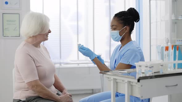 Crop View of Female Medical Nurse in Protective Mask and Safety Gloves Filling Syringe with Vaccine