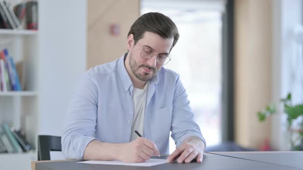 Pensive Man in Glasses Writing on Paper Thinking