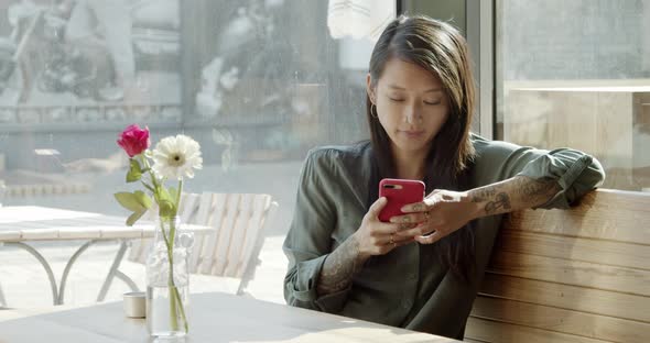 Woman sitting in cafe using her smartphone