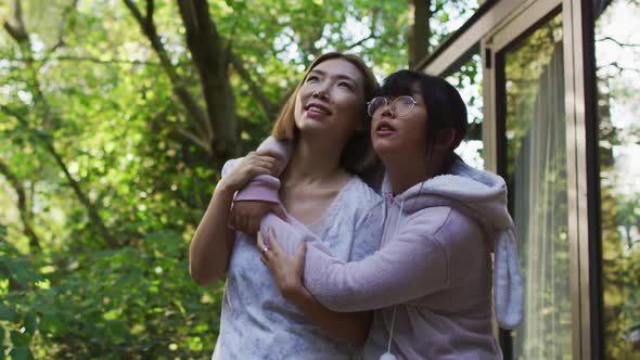 Asian mother and daughter embracing in garden and smiling