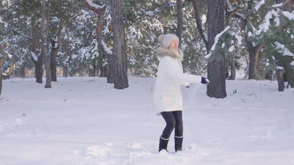 Happy Cute Girl in Warm Winter Clothes Jumping Having Fun and Throwing Snow