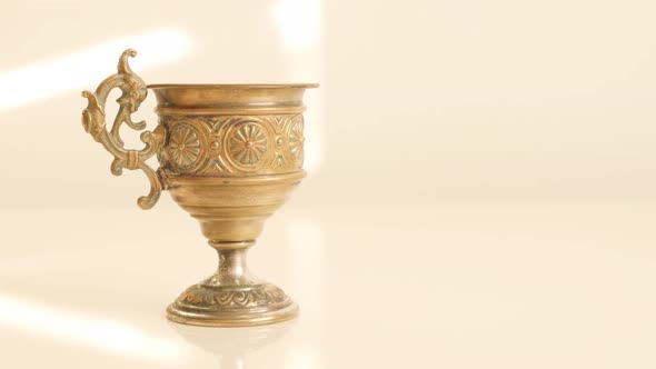 Holly grail look like ancient object made of brass on white reflective surface 4K 2160p UltraHD foot