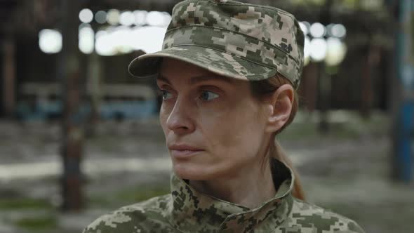 Female Soldier Looking at Camera at Destroyed Factory