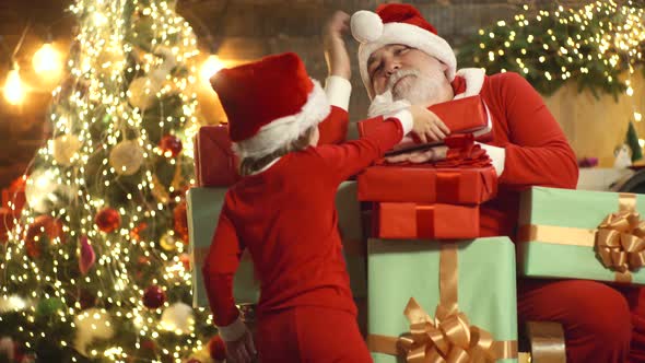 Santa Claus and Child with Christmas Gift Boxes at Home. Grandfather with Child Prepare Xmas or New