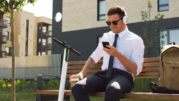 Businessman with Cellphone, Headphones and Coffee