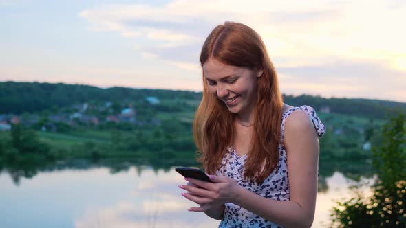 Attractive Girl Surfing Internet Social Media Stands Near Lake Play Her Phone