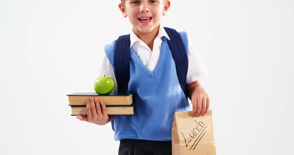 Smiling schoolboy holding books and lunch