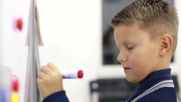 Boy Writing on Blackboard at School Solving Exercises