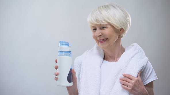 Smiling Old Female With Towel and Water Bottle Smiling at Camera Wellness