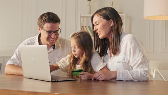 A Happy Family Uses a Laptop for Online Shopping, Sitting at Home.