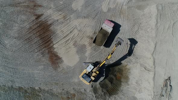 Aerial View: An Excavator Is Pouring Gravel Into a Truck, Quarry, Mining, Industrial Production