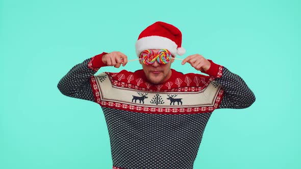 Funny Man in Red New Year Sweater Holding Candy Striped Lollipops Hiding Behind Them Fooling Around