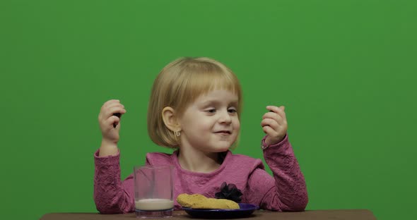 Girl Sitting at the Table and Eating Chocolate, Cookies and Drinks Cacao