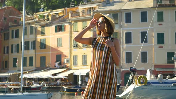 A woman walking wearing hat and backpack purse traveling, Portofino, Italy, luxury resort, Europe