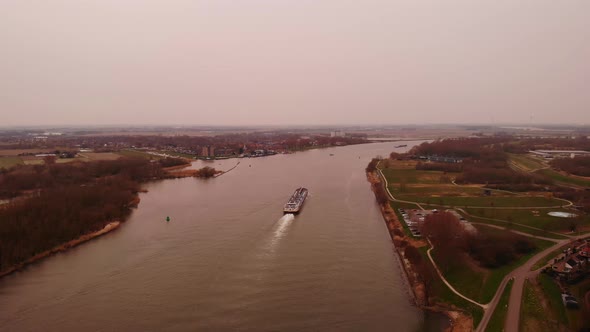 Aerial View Of Ship Travelling Along Oude Maas In Puttershoek Through Orange Dusty Air On Cloudy Day