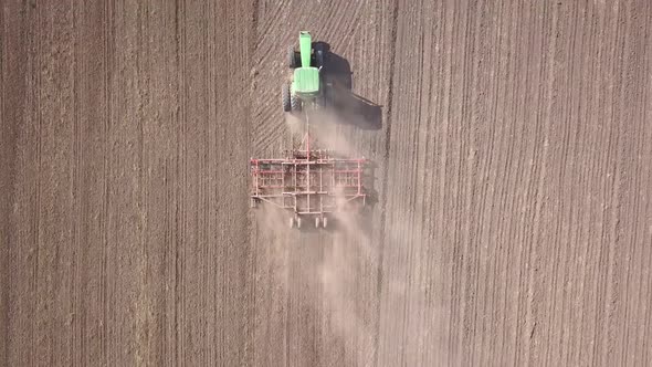 Top Down Aerial View of Green Tractor Cultivating Ground and Seeding a Dry Field