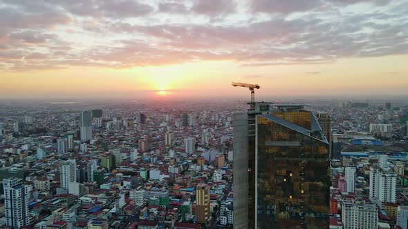 Golden Tower With Industrial Crane On Rooftop During Sunset In Phnom Penh, Cambodia. - aerial