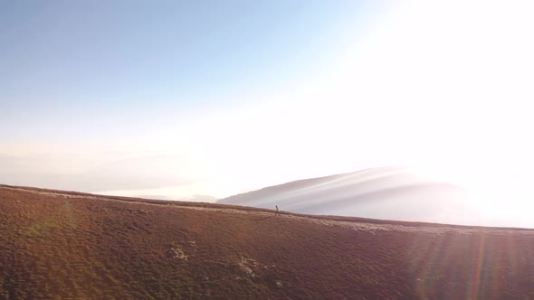 Aerial Orbit Shot Around Hiker Walking on Mountain Road