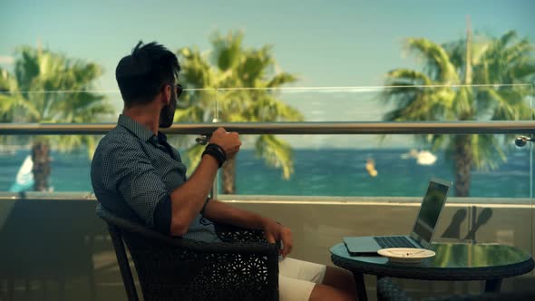 Businessman In Sunglasses. Businessman Drinking Tea On Vocation Resort. Man Sitting On Cafe At Sea.