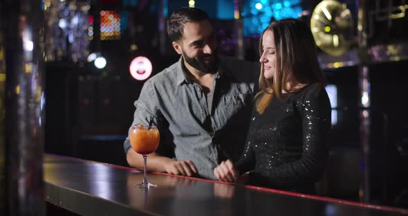 Confident Young Middle Eastern Man Coming To Charming Caucasian Girl Dancing Next To Bar Counter