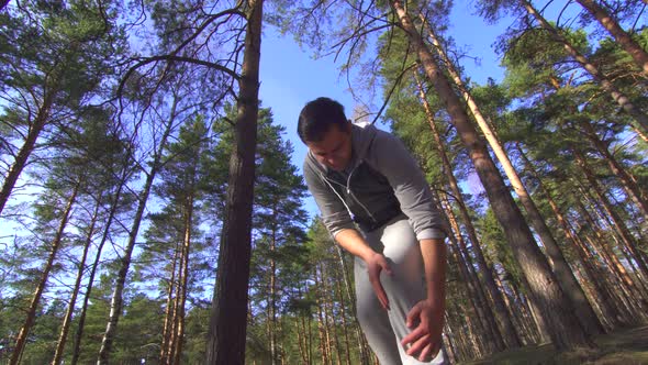 Male Athlete During a Jog Gets Knee Injury in a Sunny Forest