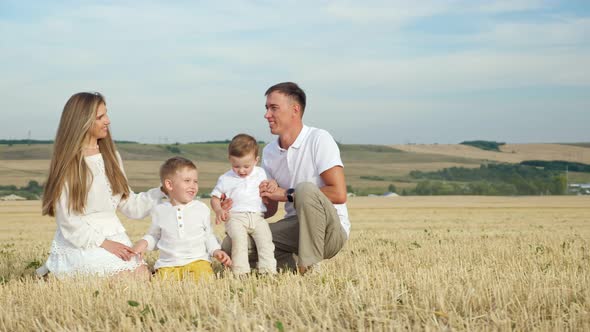 Parents with Small Sons Sit Among Field and Rest Smiling