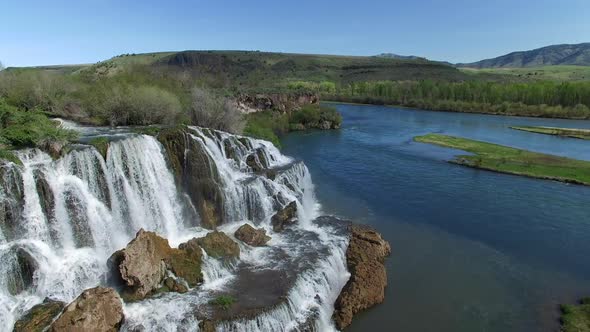 Flying view of waterfall flowing over edge into river