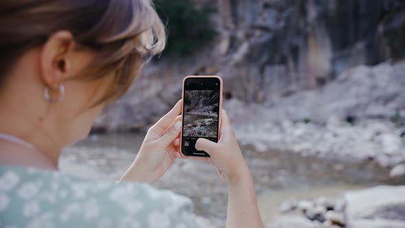 Pregnant Girl Stands Near a Mountain River and Takes Pictures on the Phone