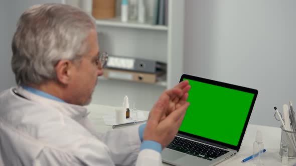 Male Doctor Treats Hands with Antiseptic and Uses Laptop with Green Screen Chroma Key for Work
