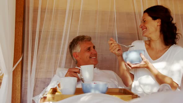 Couple having breakfast in canopy bed 