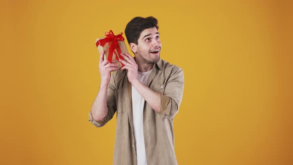 Male is Smiling Shaking Gift Box Trying to Guess What is There Inside