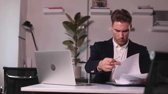 Businessman Working with Documents and Laptop Sitting at Table in Modern Office Spbi