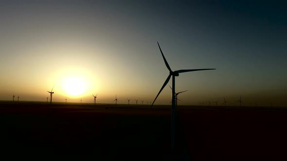 Wind Turbines Regenerative Source of Energy in the Warm Glow of Sunset. Silhouette. Aerial Survey