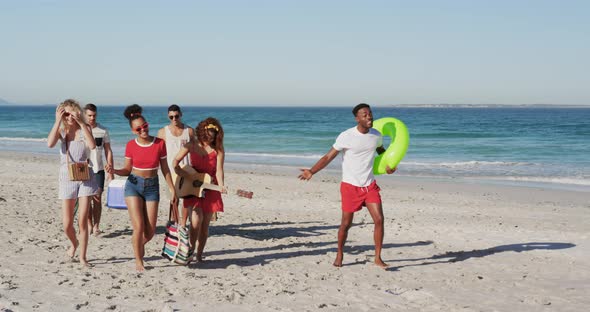 Young adult friends on holiday walking along a beach 4k