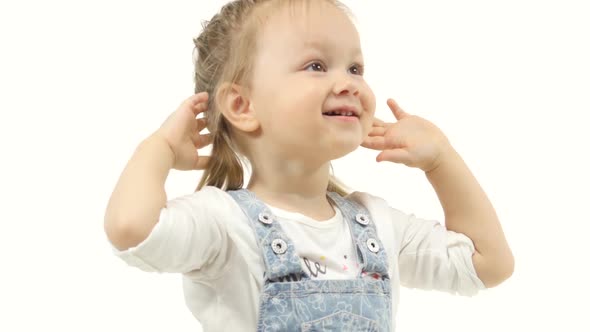 Little Girl Raises Her Hands Up Behind Her Head and Plays. White Background