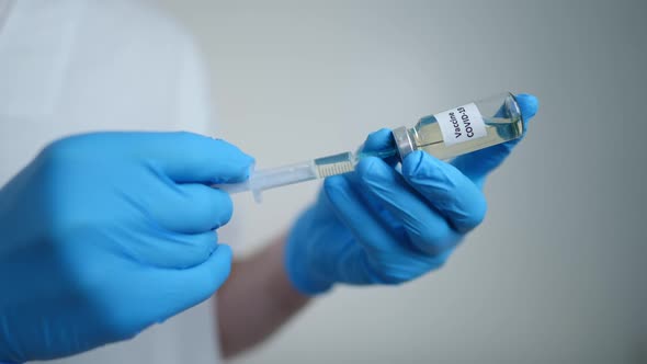 Closeup Doctor Hands in Gloves Filling Syringe with Covid19 Vaccine in Vaccination Center